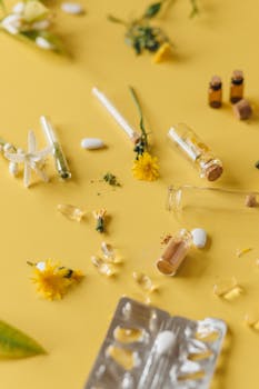 Flat lay of herbal medicines and natural ingredients with flowers on a yellow background.