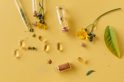 Free Herbal Capsules and Powder on Yellow Surface Stock Photo