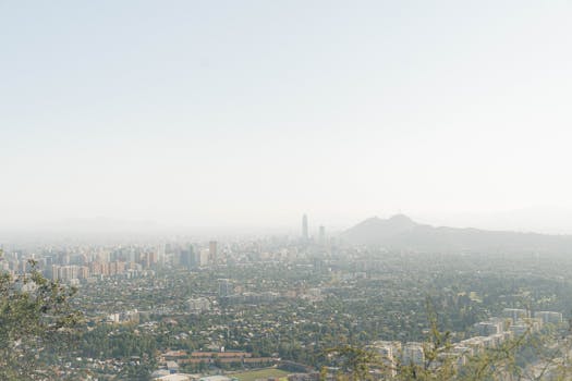 A wide-angle view of Santiago's skyline under a bright sky, capturing urban and mountainous landscapes.
