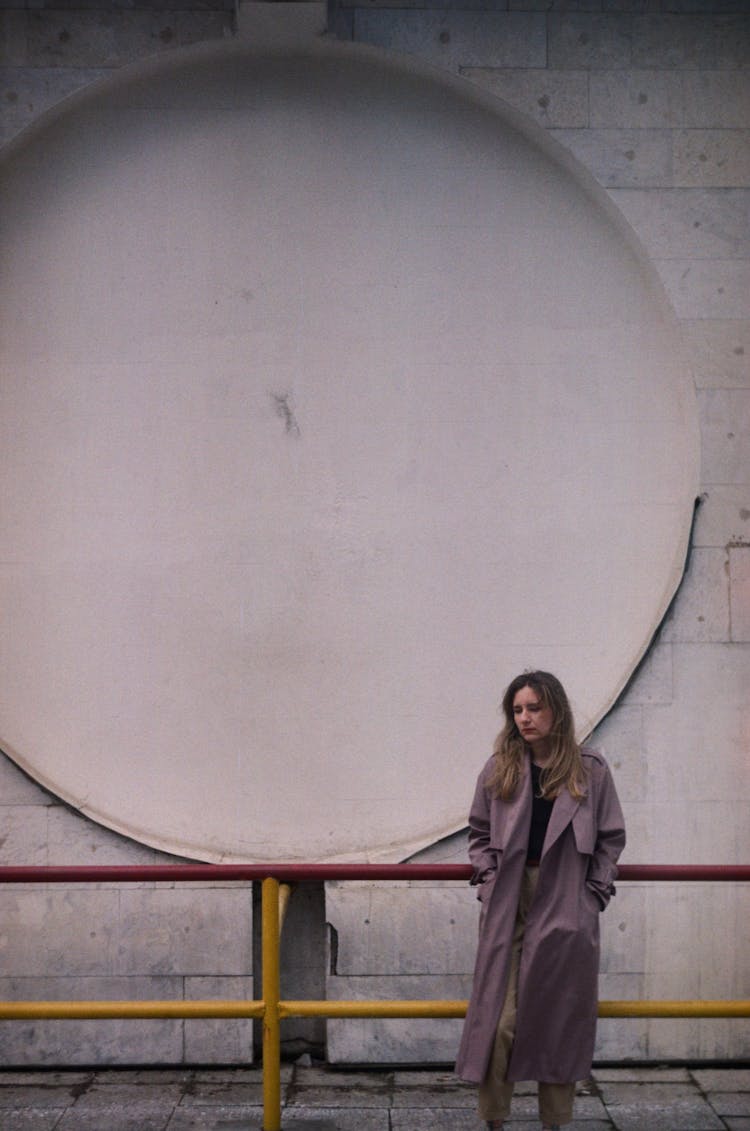 A Woman In Trench Coat Leaning On Steel Railings