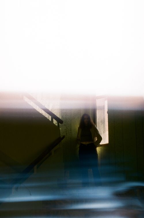 Free A mysterious silhouette of a person standing on a dimly lit staircase with a haunting atmosphere. Stock Photo