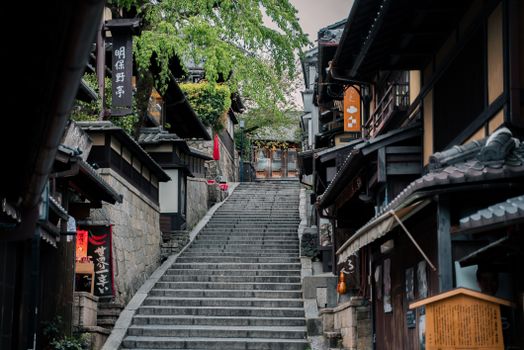 Charming historic street in Kyoto featuring traditional wooden buildings and a stone staircase.