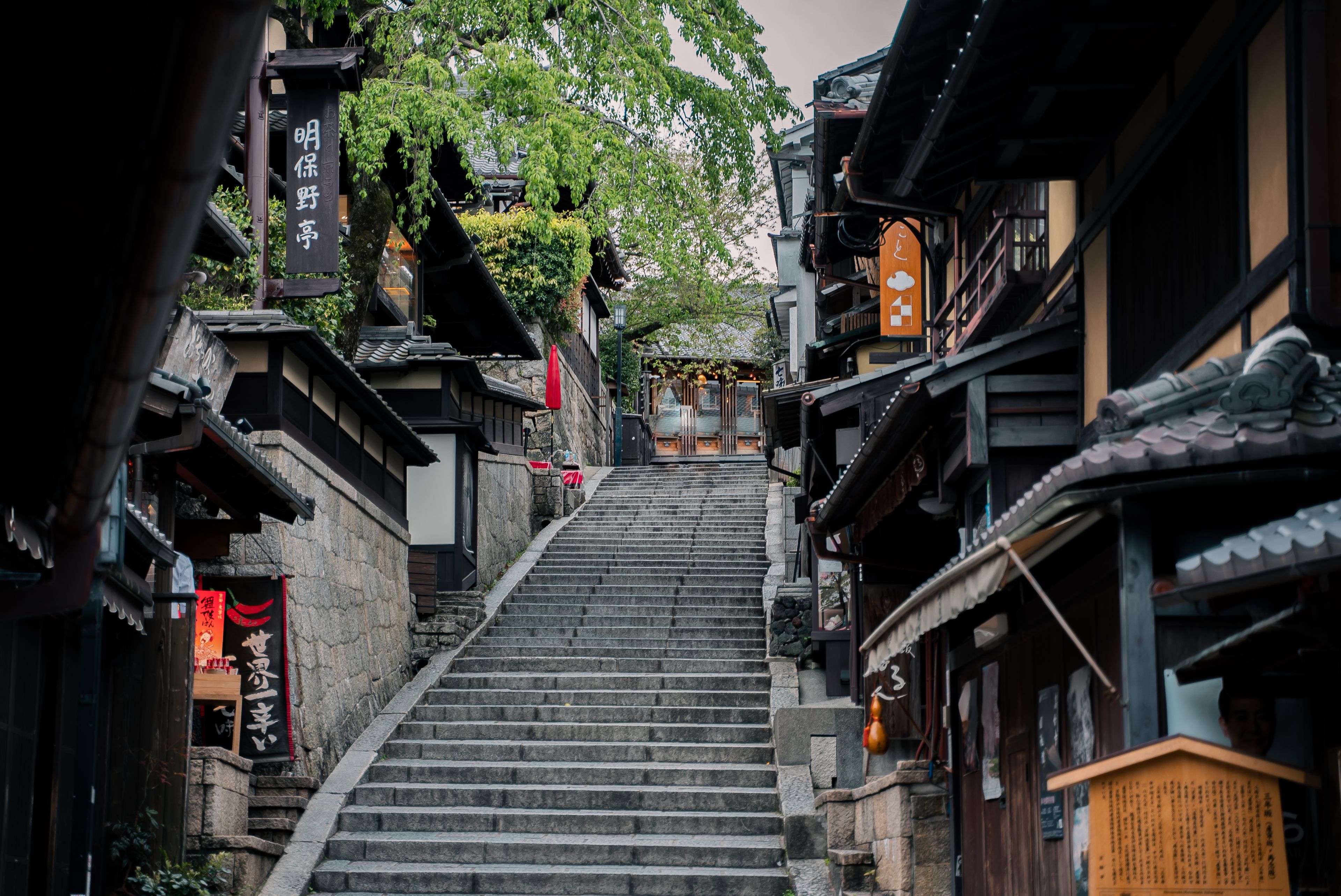 Charming historic street in Kyoto featuring traditional wooden buildings and a stone staircase.