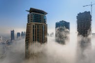 白天的雾气中，现代摩天大楼从雾蒙蒙的迪拜天际线拔地而起