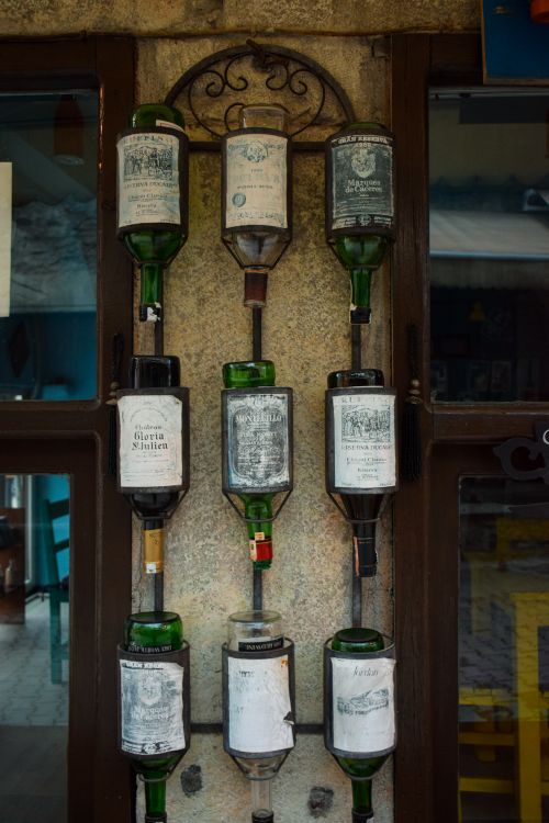 Free Antique liquor bottles hung upside down on a decorative metal rack in a cozy indoor bar setting. Stock Photo