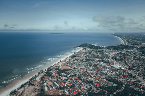 Free Amazing drone view of residential houses located in city near sandy beach washing by foamy waves of blue ocean against cloudy sky Stock Photo