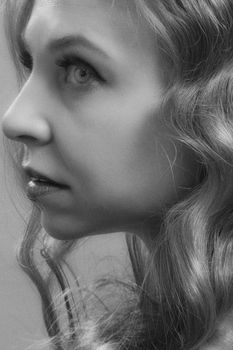 Black and white side portrait of a woman with wavy hair, capturing grace and subtle emotion.
