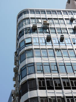 Contemporary multistory building facade with glass windows under a clear blue sky in Hong Kong.