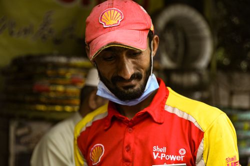 Free Shell V-Power employee wearing a red and yellow uniform in Lahore, Pakistan. Stock Photo