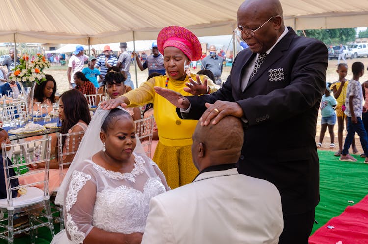 An Elderly Man And A Woman Praying Over A Couple Getting Married