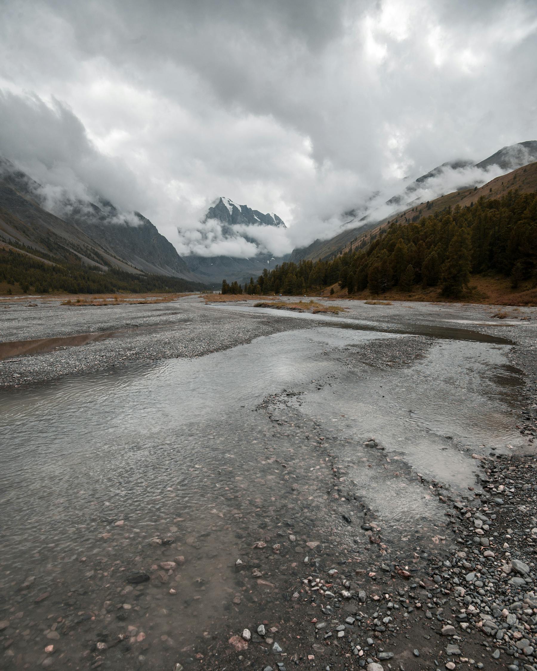 Shallow river against high ridges under cloudy sky · Free Stock Photo