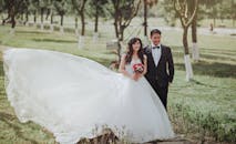 在明媚的阳光下，新娘和新郎微笑着的迷人户外婚纱照