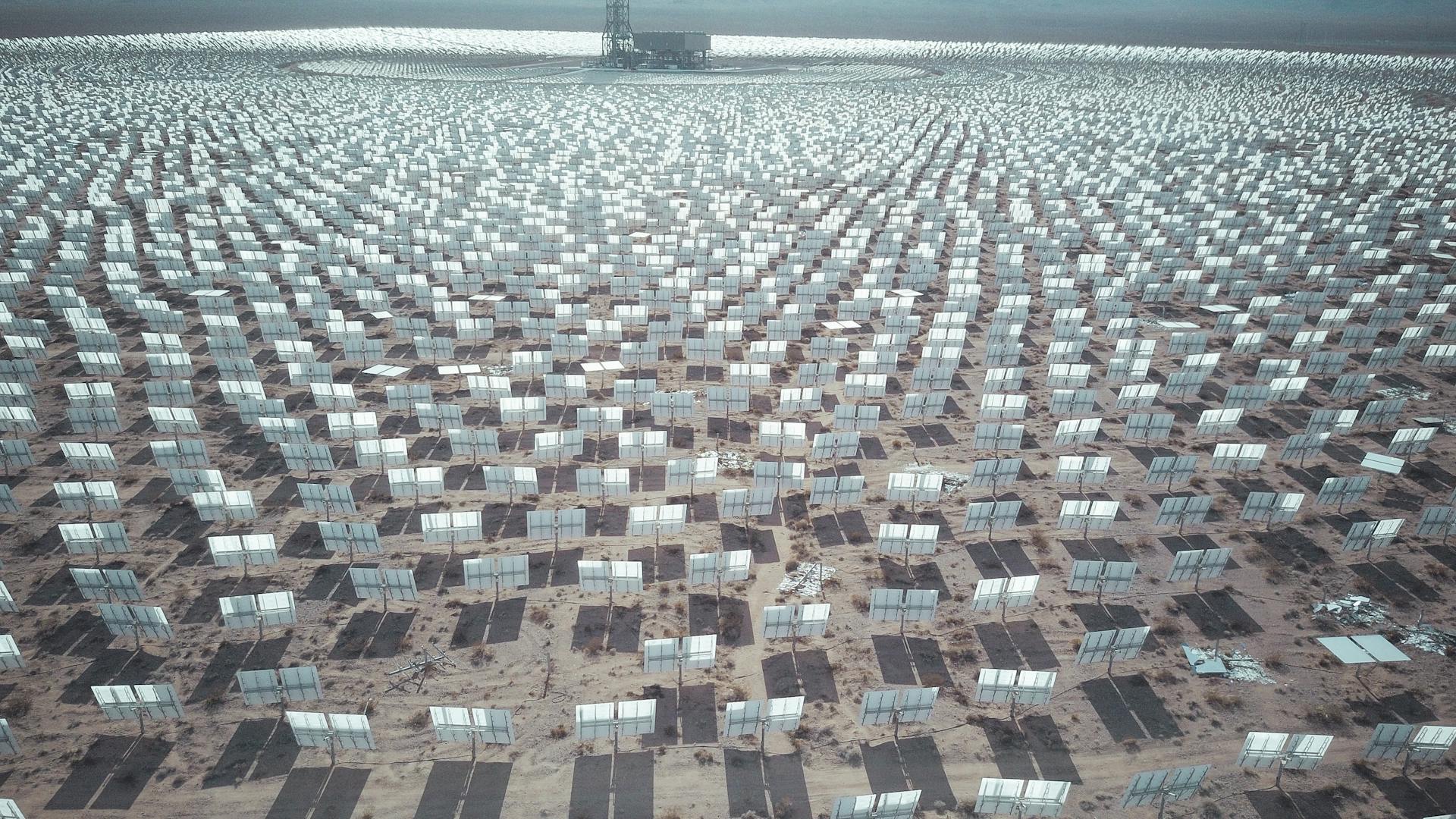 Aerial view of expansive solar panel array in a desert landscape generating renewable energy.