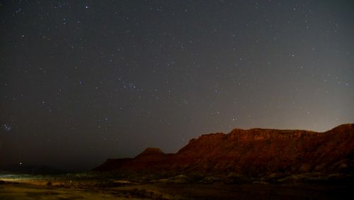 Free A serene night scene featuring a starry sky over a desert canyon landscape under calming evening light. Stock Photo