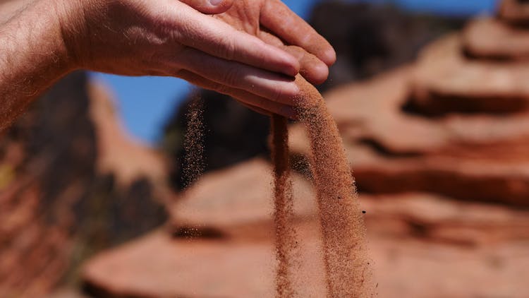 A Person Pouring Sand From Hands