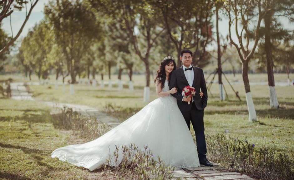 A happy couple in wedding attire poses outdoors in a scenic park setting. A happy couple in wedding attire poses outdoors in a scenic park setting.