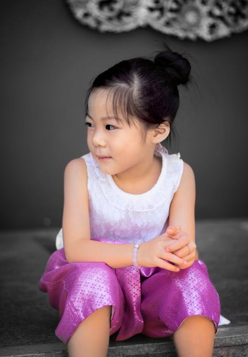Close-Up Shot of a Girl Sitting on Gray Surface