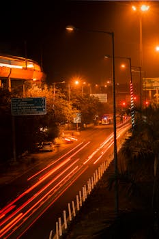 Long exposure shot of urban traffic under streetlights showcasing dynamic light trails and city nightlife.