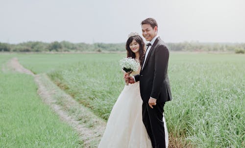 男人和女人在稻田之间穿婚纱和西装