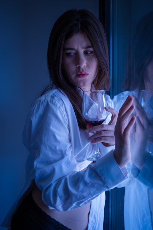 Free Woman In White Long Sleeves Leaning on a Glass Window Stock Photo