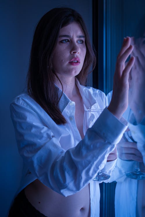 Woman in Long Sleeves Holding a Glass Window