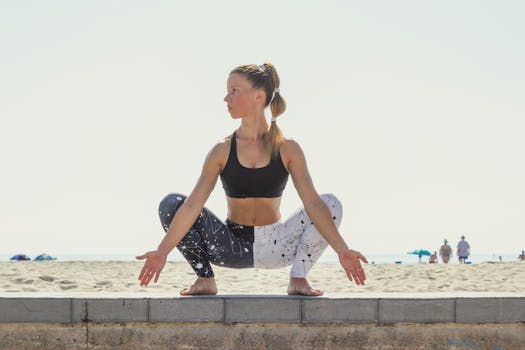 Young woman in yoga pose on a sunny beach, showcasing strength and flexibility.