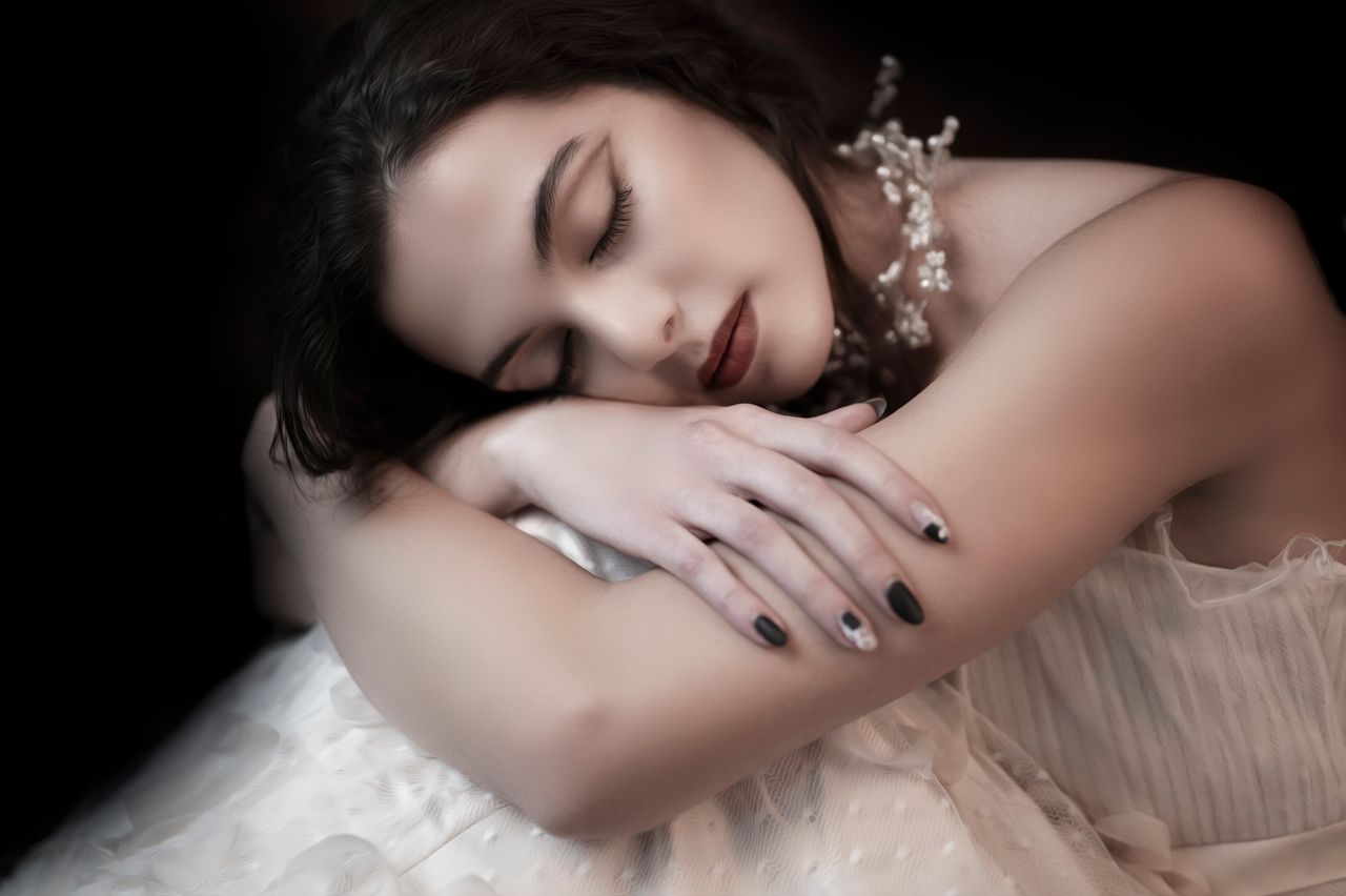 close up of a serene woman in a white dress resting elegantly with a p