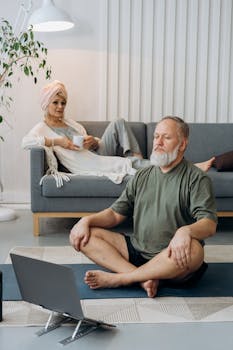 Elderly couple enjoying wellness activities at home, with one meditating on a yoga mat and the other relaxing with tea.