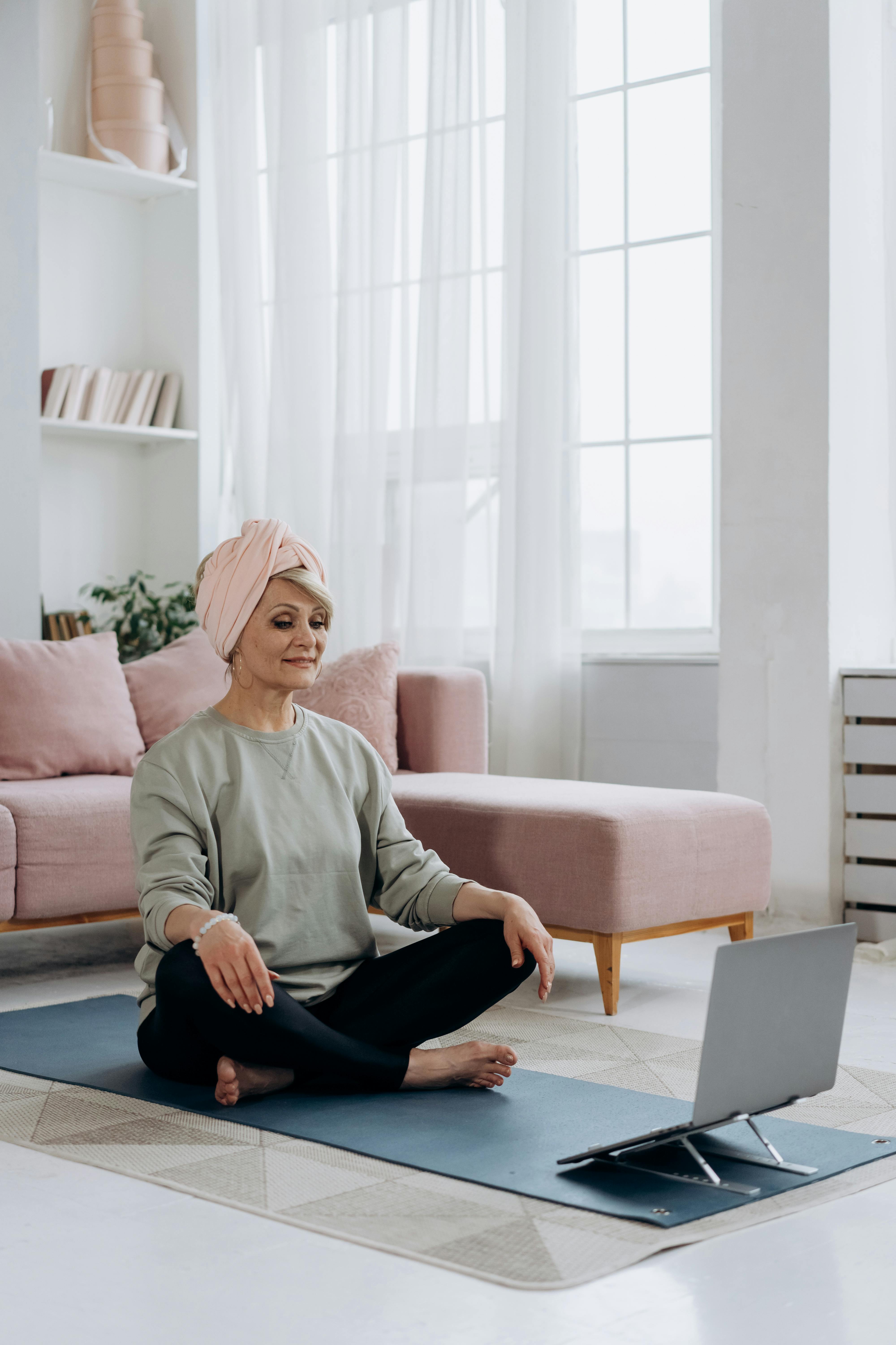 elderly woman in a headwrap sitting on a yoga mat