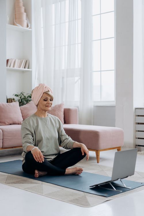 Free Elderly woman in a turban practices yoga online in her living room. Stock Photo