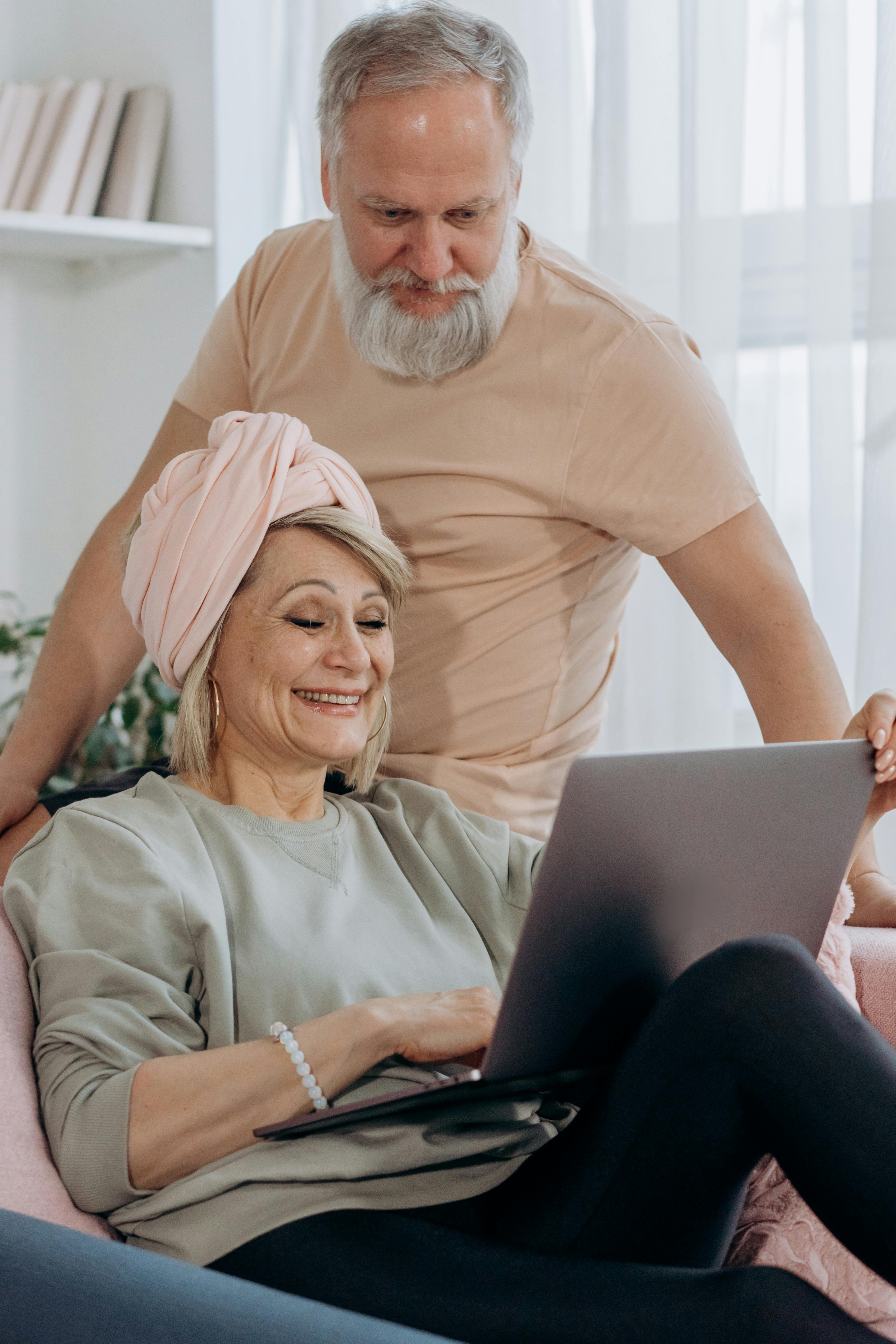 an elderly couple looking at the laptop screen