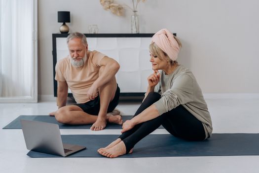 Elderly couple practicing yoga online at home, promoting wellness.