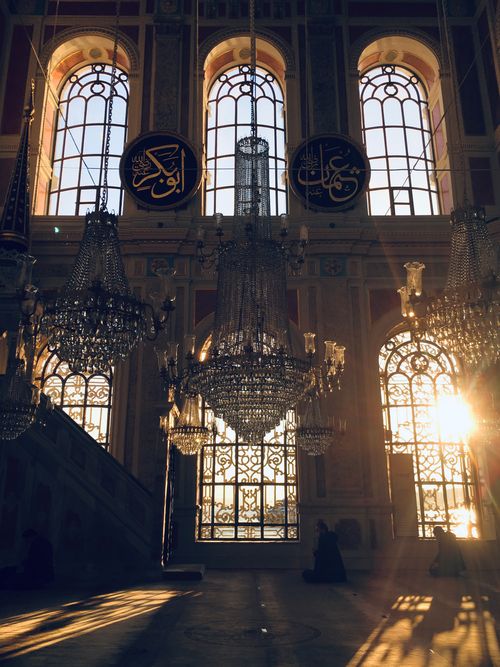 Free Chandeliers glow in sunlit interior of an Istanbul mosque, reflecting intricate architecture. Stock Photo
