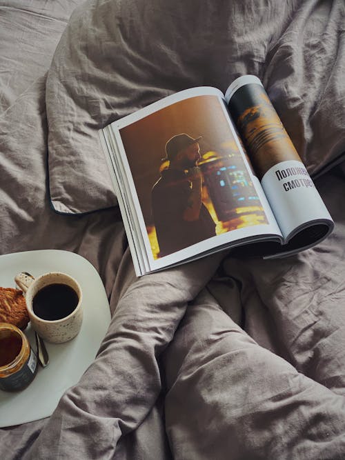 Magazine and plate with coffee and tasty dessert on blanket