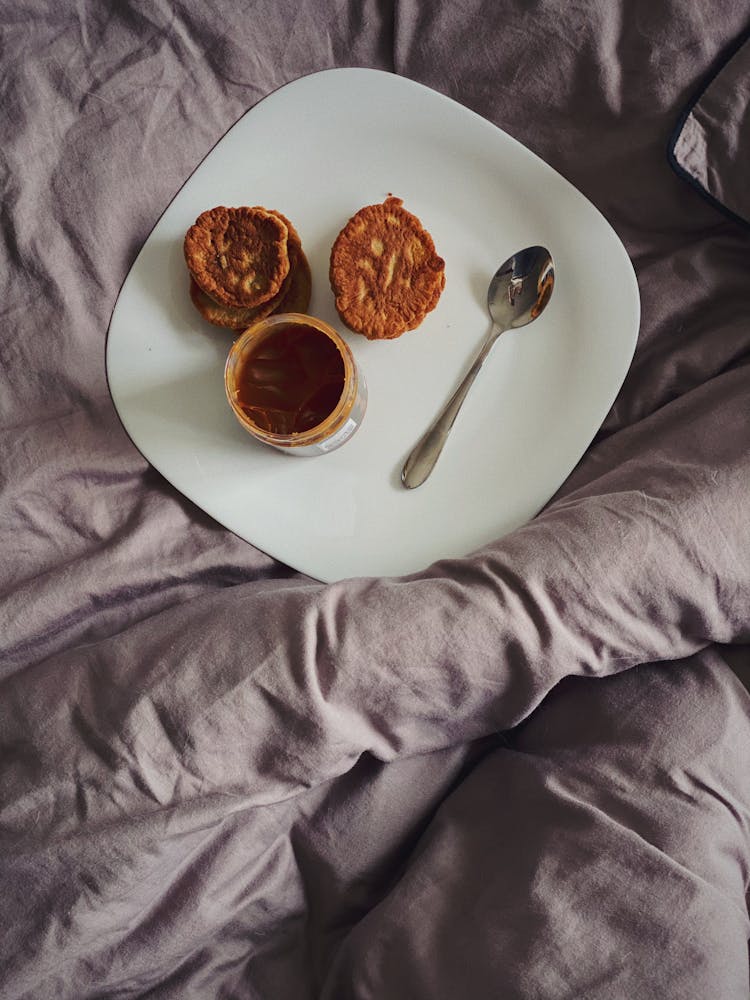 Delicious Pancakes With Jar Of Chocolate Spread Placed On Bed