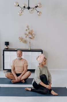Elderly couple practicing yoga together indoors for wellness and flexibility.