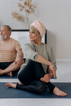 Elderly man and woman doing yoga indoors. Focus on relaxation and fitness.