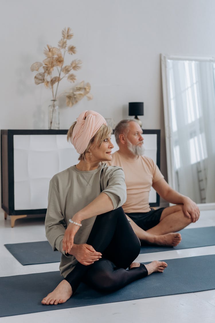 An Elderly Man And Woman Sitting On The Floor While Doing Yoga