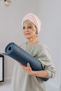 Middle-aged woman holding a yoga mat, ready for a workout at home.