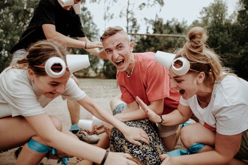 A Man with Women Wearing Paper Cup Headbands Laughing 