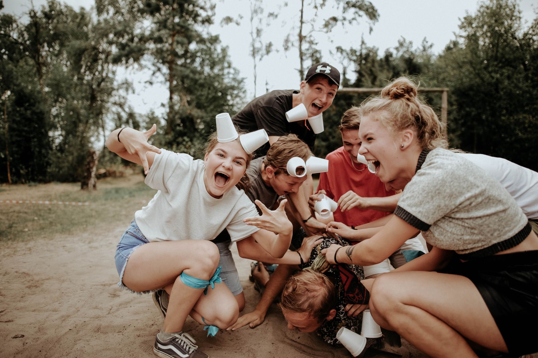 Energetische groep tieners die buiten spelen, met lachende stemmen en een stapel bekers.