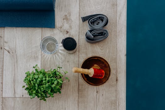 Flat lay of yoga and meditation accessories including mat, straps, and singing bowl.