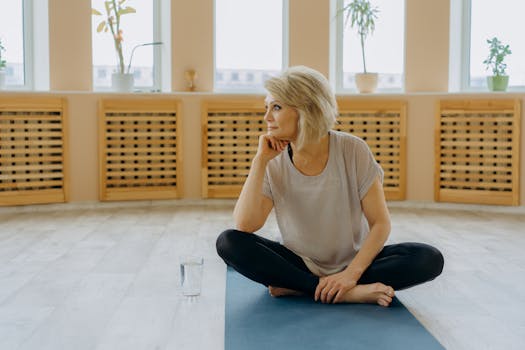 A senior woman sitting on a yoga mat indoors, reflecting peacefully. Perfect for wellness and fitness concepts.
