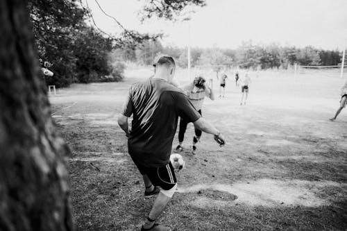 Grayscale Photo of a Group of People Playing Football 