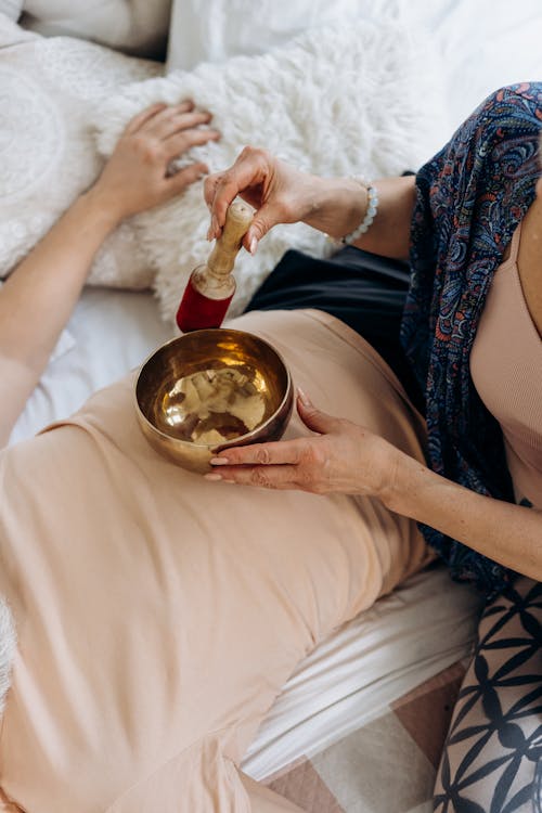 Woman Holding Singing Bowl on Person's Stomach
