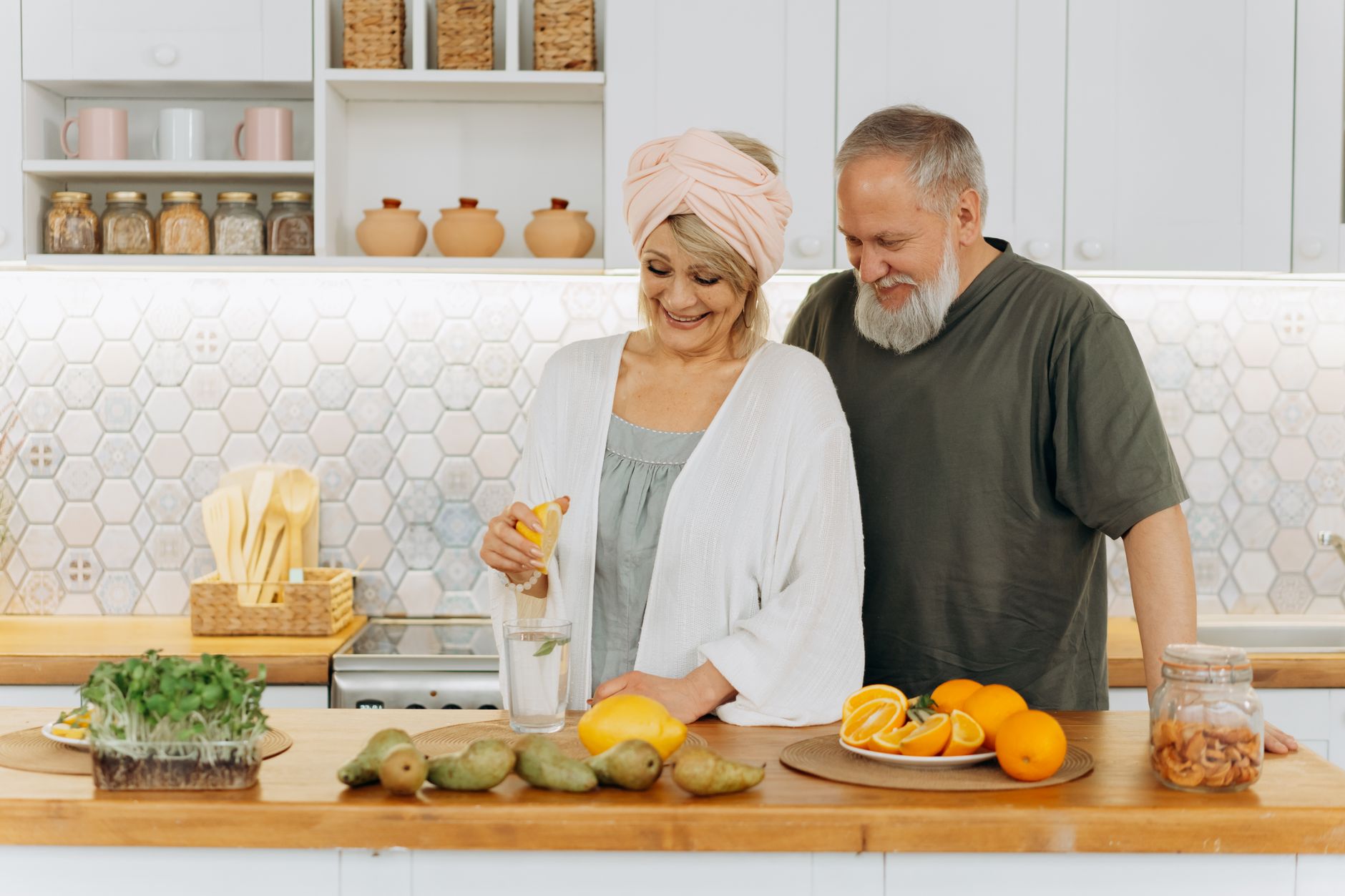 lifestyle for brain health — Senior couple squeezing citrus in a bright kitchen setting, promoting healthy living and joyful togetherness.