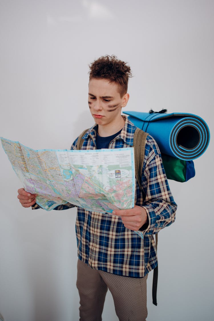 A Backpacker In A Plaid Shirt Looking At The Map