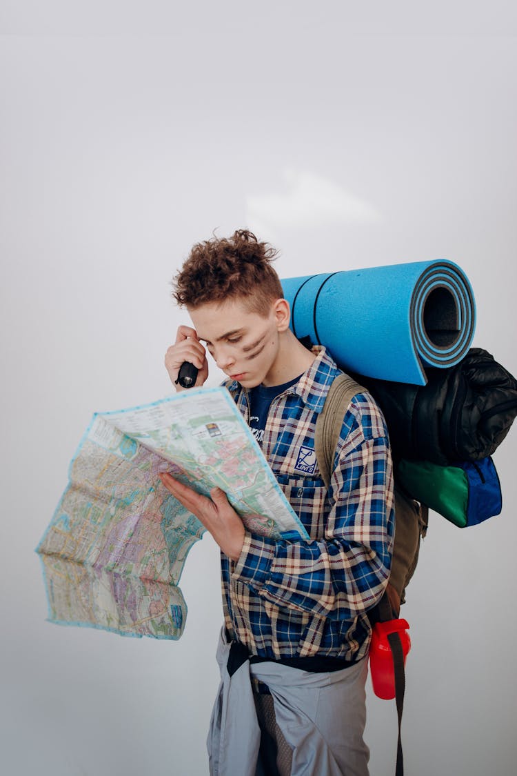 A Boy Holding A Flashlight While Looking At The Map