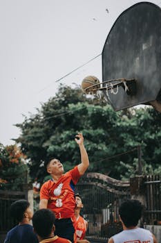 Dynamic outdoor basketball game showcasing enthusiastic players and a shot in motion.