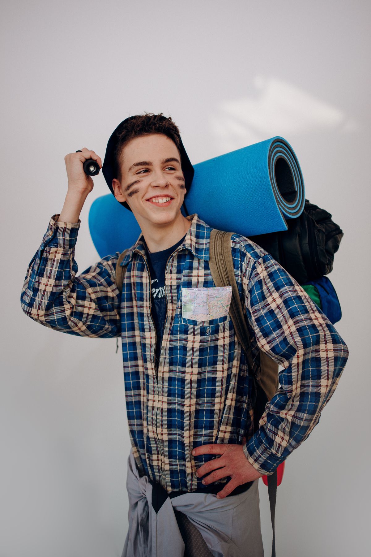 Adult man in a plaid shirt with a backpack holding a flashlight for halloween costume ideas for adults